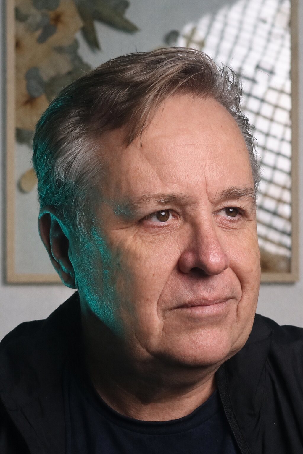Ken Metcalf in a close portrait, wearing black against a softly lit interior.